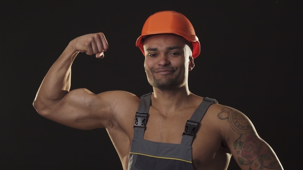 Muscular Ripped Sexy African Male Builder in Workwear and Hardhat Flexing Muscles