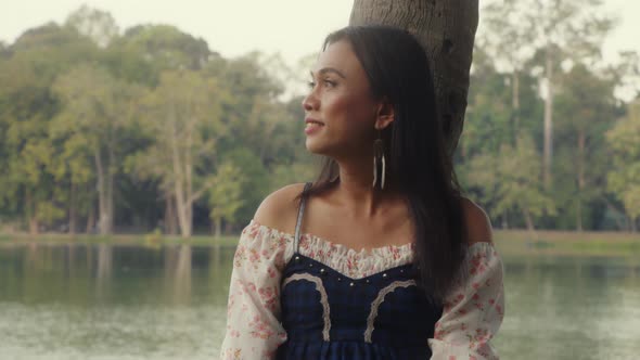 Transgender Asian Woman Leaning Against a Tree in the Park Enjoying the Moment