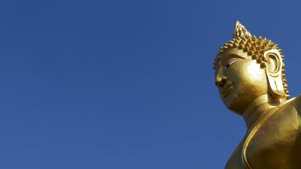 Statue of a Large Golden Buddha Against a Blue Sky in Thailand Temple alt