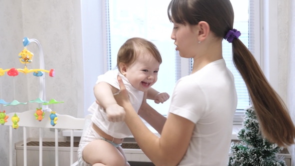 Young Mother Plays with a Child in the Children Room and They Laugh