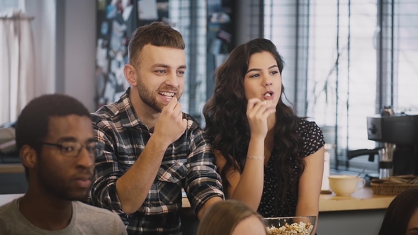 Cute Couple Watch Funny Film on TV with Friends. Caucasian Guy and Girl Sit Together, Eat Popcorn