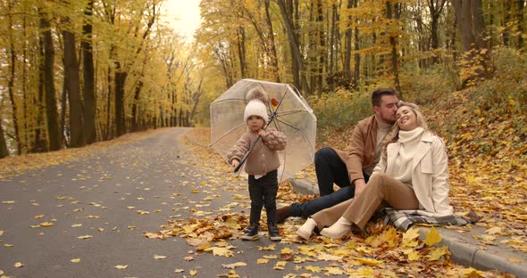 Happy Family Sitting on the Alley in the Autumn Park
