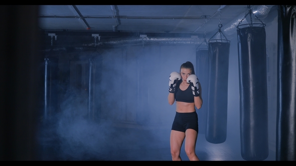 Young Woman Shadow Boxing in a Smoky Gym