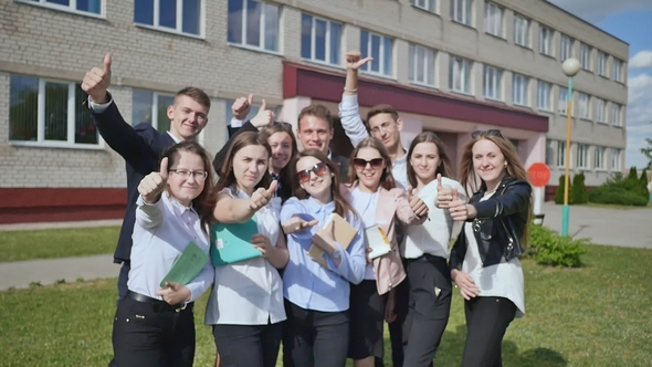 Happy Students on the Background of His School Raises His Hands with a Finger Up