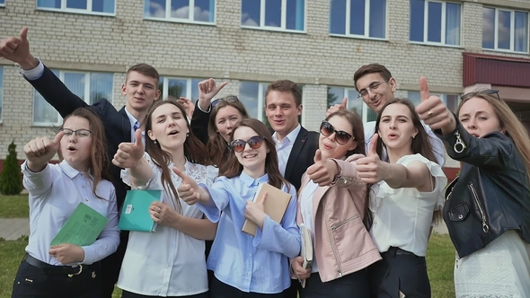 Happy Students on the Background of His School Raises His Hands with a Finger Up