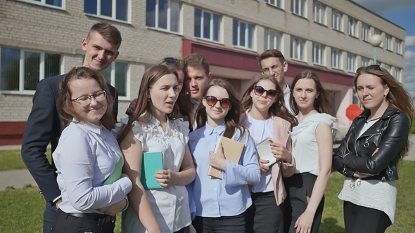 Happy Students on the Background of His School Raises His Hands with a Finger Up