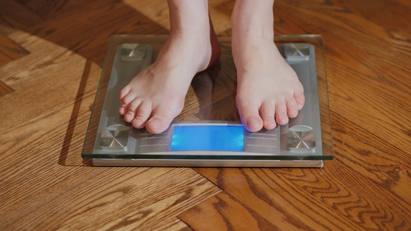 A Barefoot Man Measures His Weight on a Floor Scales