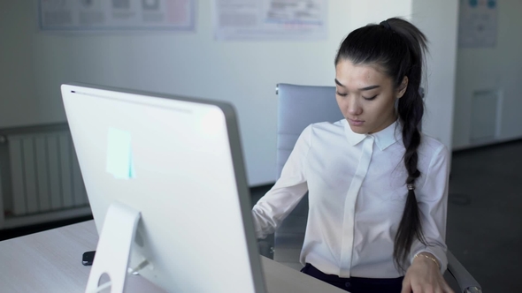 Asian Business Woman Is Sitting on Desk and Starts Working at Computer.