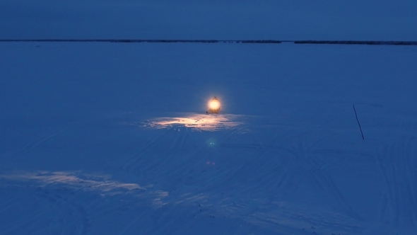 A Snowmobile Is Riding at Night Lighting the Way