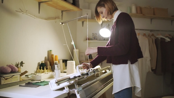 Young Woman Working on Knitting Machine in Home Workshop