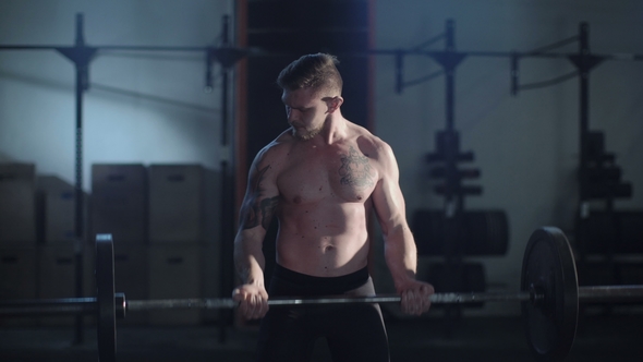 Tattooed Sportsman Lifting Barbell in Gym