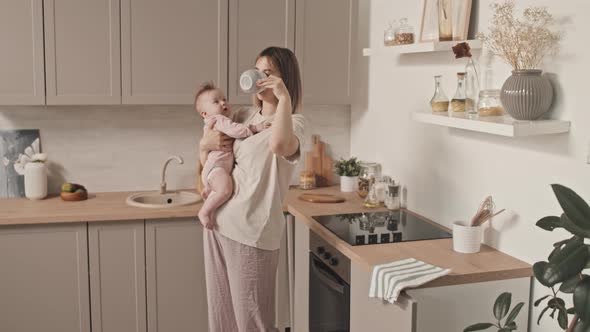 Mom Holding Baby and Drinking Coffee