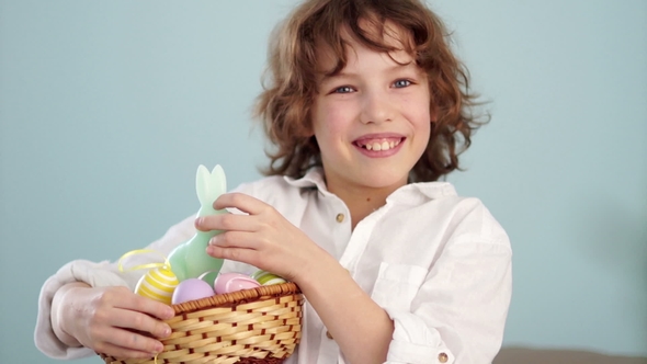 A Child Holds a Easter Bunny and a Set of Decorative Easter Eggs. The Boy Laughs Cheerfully.