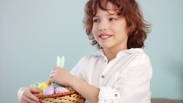 Cheerful Schoolboy with a Basket of Easter Eggs. Curly-haired Boy Laughs Fun