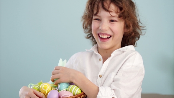 Portrait of a Curly Red-haired Boy with a Basket of Easter Eggs in his Hands