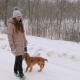 Teenager Girl Walks with Dog in Park in Snowstorm and Smiles - VideoHive Item for Sale