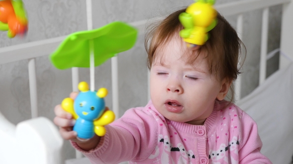 Baby Is Playing in Toys in His White Crib