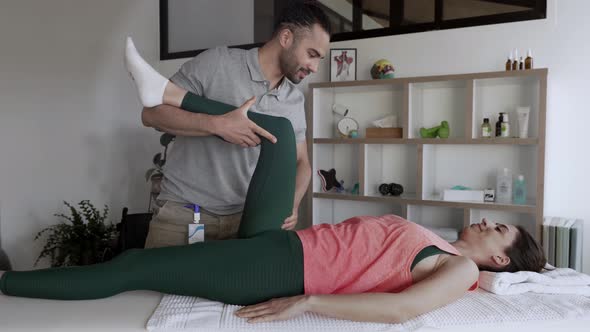 Physiotherapist doing hip mobility exercise on female patient