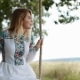 Attractive Blonde Girl in a Stylish, Trendy, Embroidered Dress Sways on a Wooden Swing Seat in the - VideoHive Item for Sale