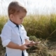 Sweet Baby-blogger Stands in the Middle of Field, Uses Smartphone, Playing Games, Posting Photos - VideoHive Item for Sale