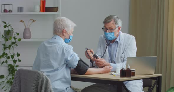 Two People in Clinic Senior Male Doctor Measuring Patient's Blood Pressure During Regular