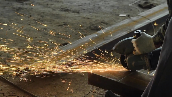 Shot of a Professional Builder Grinding on a Big Piece of Metal on a Contruction Site