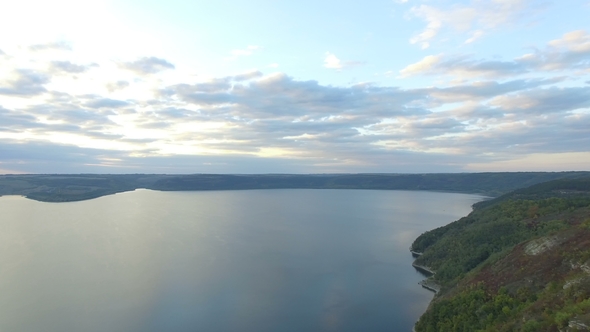 Great Sunset on the Lake Between the Mountains. A Couple Hugging at the Edge of the Cliff