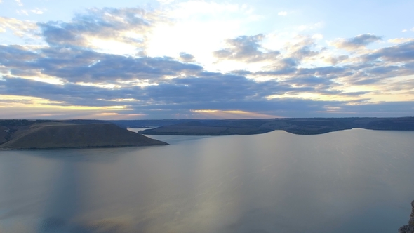 Great Sunset on the Lake Between the Mountains. A Couple Hugging at the Edge of the Cliff.