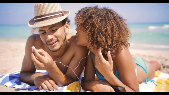 Couple Lying with Music on Beach