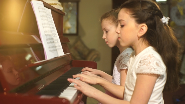 Cheerful Beautiful Small Girls Play Piano Together