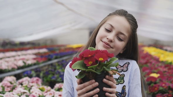 Happy Girl Choosing and Smelling Flower Seedling