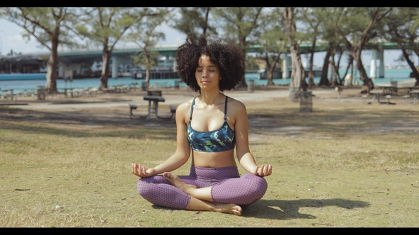Content Woman Meditating in Sunlight in Park