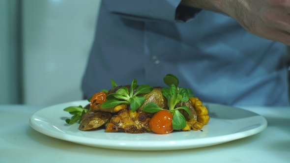 Chef Finishing and Garnishing Food He Prepared, a Dish with Pork Meat and Vegetables