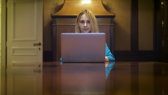 Serious Woman Working on Notebook Computer Sitting at Table in Home Studio