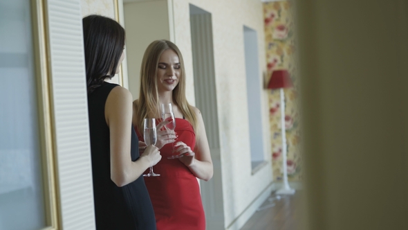 Three Pretty Girls in Dresses Having a Small Talk and Drinks Champagne