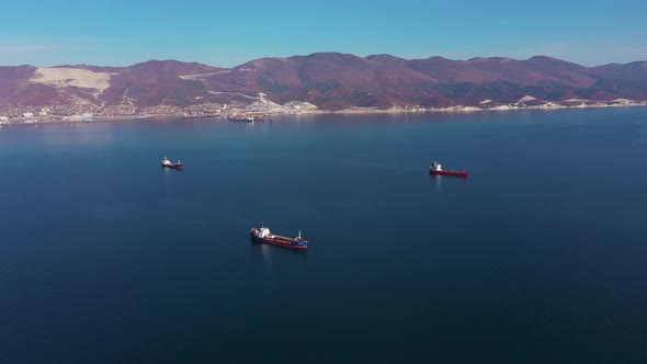 Aerial View, Vessels Drift on Calm Blue Ocean Surface Against Hilly Coast