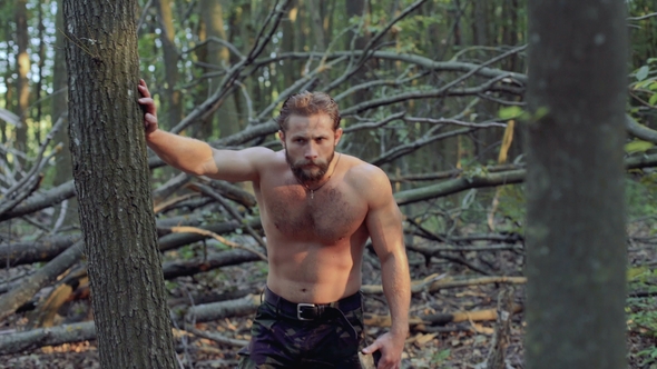 Handsome Bearded Man Walks with Ax in the Forest