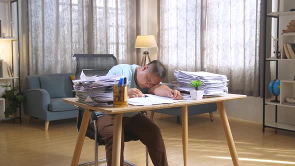 Fat Asian Man Sleeping Due To Working Hard With Documents At The Office