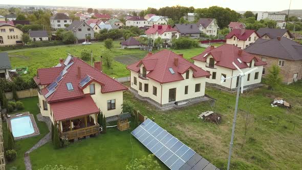 Aerial View of Suburban Homes and Private House with Green Grass Covered Yard Solar Panels on Roof