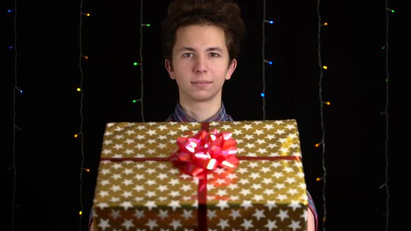 Boy with a Gift Box on Black Background. Gift Box with Ribbon for Happy New Year, Merry Christmas