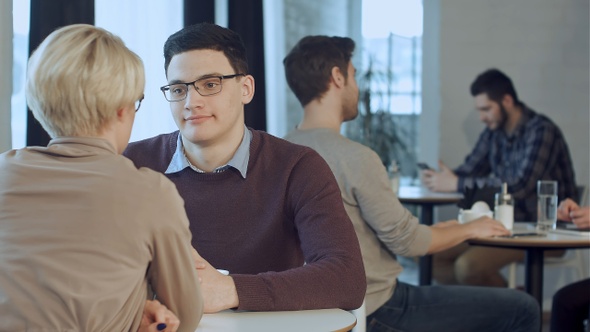 Young couple talking and drinking coffee near the window in cafe