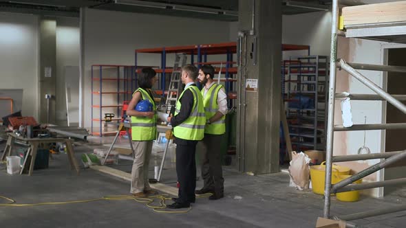 Men and woman discussing with digital tablet at construction site