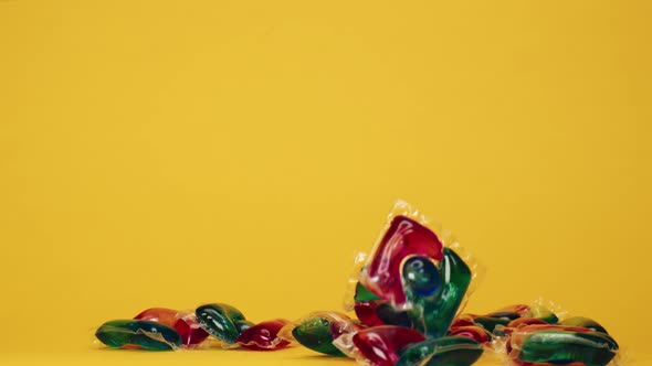 Throwing Washing Gel Pods on Yellow Background Capsules with Detergent for Washing Machines