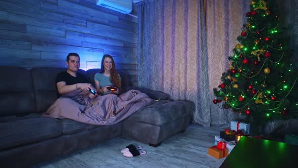 Young Couple Sitting on a Couch and Playing Games on a TV