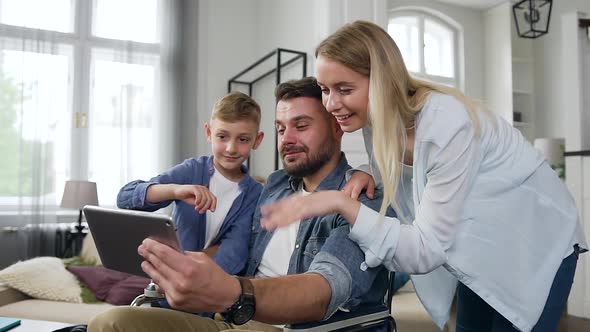 Smiling Boy, Woman and Man in Wheelchair Talking on Applying i-pad