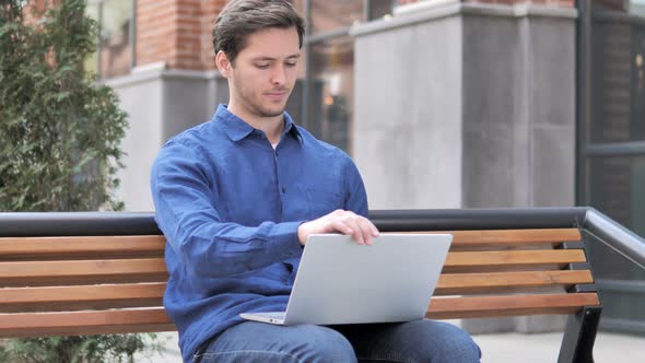 Young Man Leaving Bench after Closing Laptop