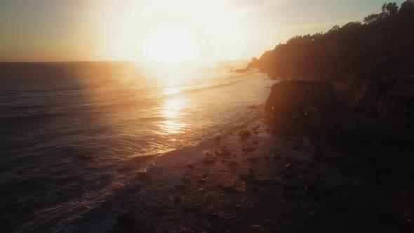 Aerial shot of huge rock on sandy dusky oceanside at El Matador Beach, Malibu, Califronia, USA