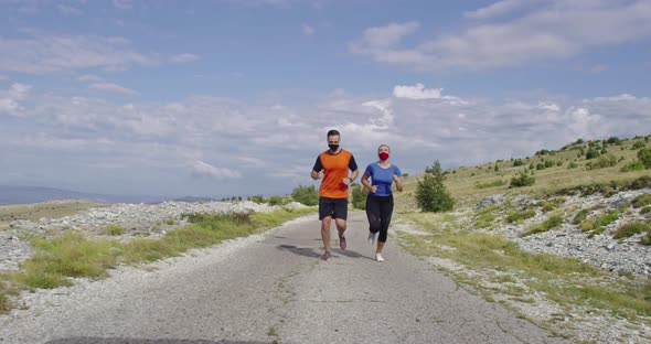 Young Couple in Medical Face Masks Running on the Road During a Pandemic