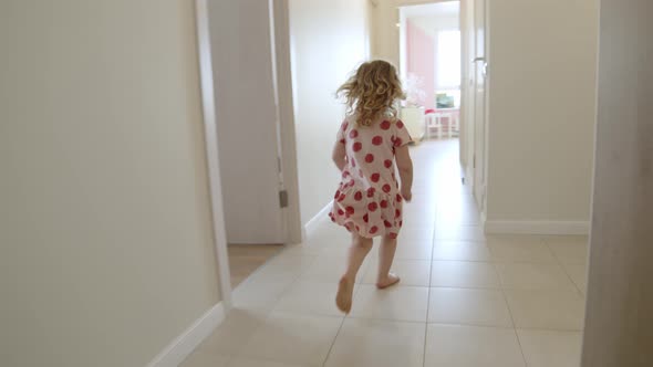 Follow Handheld Shot Happy Child Runs Through New Apartment in Pink Dress Along Corridor Barefoot on