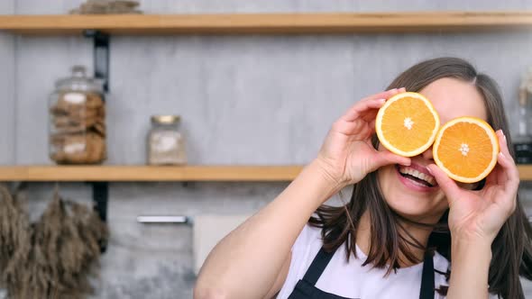 Portrait of Happy Young Girl in Apron Having Fun Dancing Posing with Orange on Eyes Medium Closeup